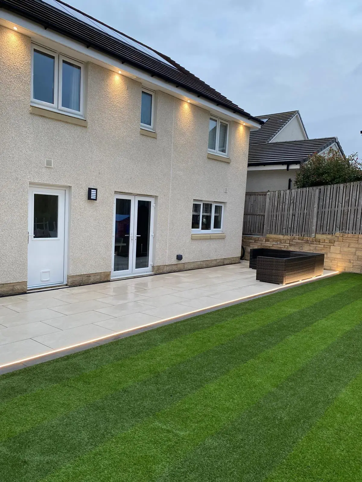 New paved patio with edge lighting and a striped lawn at a home in the Central Belt